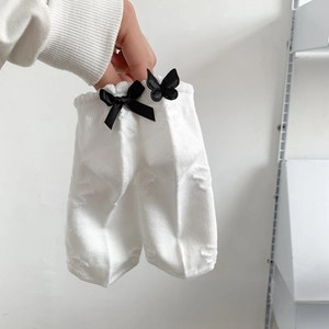 Close-up of white JK lace socks with black 3D butterflies and jacquard knit texture