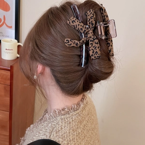 Detailed view of leopard print bow hair claw clip worn on model's head for styling