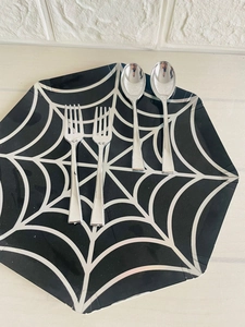 Detail of silver disposable spoons and forks set on a black spider web plate for Halloween