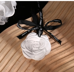 Macro shot of camellia plaster diffuser with black ribbon on a textured wooden background