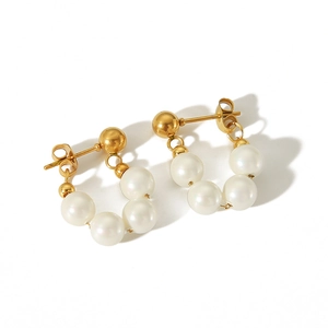 Détail de boucles d'oreilles vintage en perles avec monture dorée et perles semi-circulaires