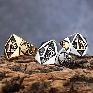 Macro detail of men's punk skull rings in gold and silver finish on textured wood