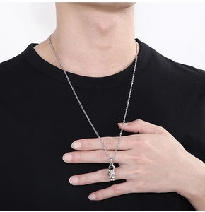 Close-up of a silver astronaut pendant on a long stainless steel chain worn by a model