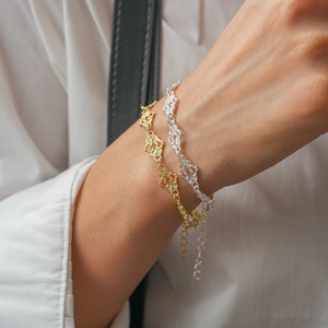 Detail of layered gold and silver bracelets with hollow heart patterns on a model's wrist