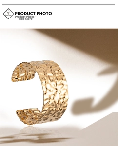 Detail of wide gold cuff bracelet featuring hand-hammered texture and striking light shadows
