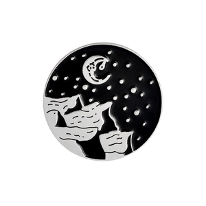 Detailed close-up of a circular enamel pin featuring stylized mountains and crescent moon