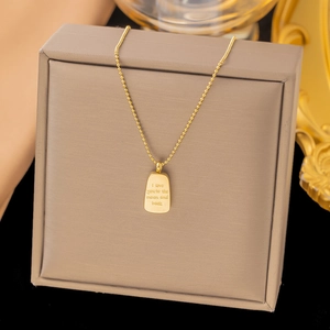 Macro detail of a gold moon and back engraved pendant on a delicate bead chain