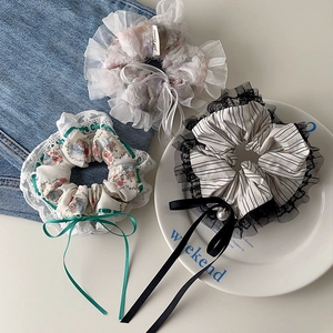 Detail of floral hair scrunchies with lace, ribbon bows and pearl on a white ceramic plate
