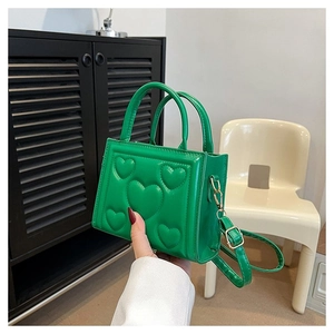 Détail du sac à main vert avec motifs cœurs en relief et garnitures dorées chic