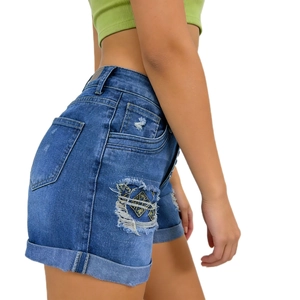 Detailed view of dark blue distressed denim shorts featuring rolled cuffs and side pocket