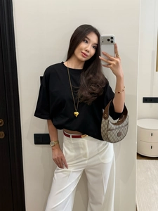 Mirror selfie showing a black short-sleeve T-shirt styled with white wide-leg trousers