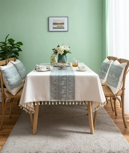 Close-up of reindeer and tree jacquard patterns with fringe tassels on a beige tablecloth