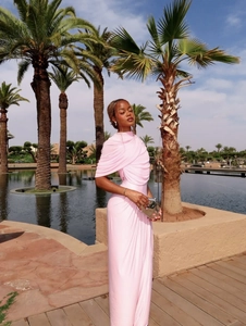 Elegant light pink sleeveless maxi dress with ruching and high neck by the resort pool