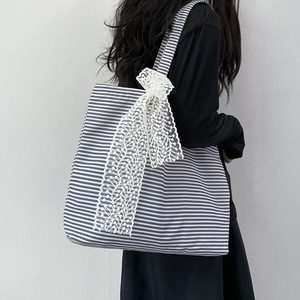 Blue and white striped canvas tote bag detail featuring a delicate white lace bow accent