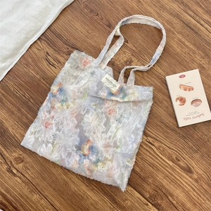 Close-up of white lace tote bag with floral patterns on a rustic wooden background
