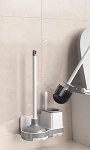 Dettaglio del set scopino e stantuffo WC a parete con base minimalista bianca e grigia