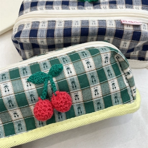 Detail of plaid cosmetic bag with handmade crochet cherries and sturdy zipper closure