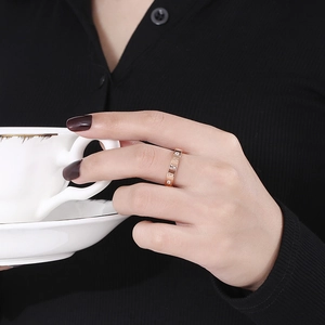 Detail of rose gold Roman numeral ring with diamonds worn while holding a white cup