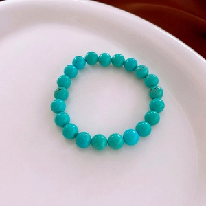Detail of turquoise bead bracelet with natural brown veins on a white ceramic plate
