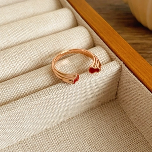 Détail d'une bague double gourde en or rose avec émail rouge dans un écrin en bois