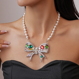Macro detail of large silver bow necklace with multi-colored gems and faux pearls
