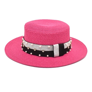Close-up of rose red boater hat featuring elegant pearl and rhinestone hatband detail