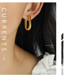 Close-up of elegant gold U-shaped thick hoop earrings worn by a model in a luxury style