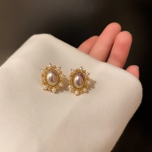 French style gold pearl earrings with shimmering accents on white silk fabric