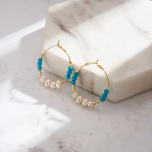 Detailed close-up of bohemian hoop earrings with white pearls and turquoise stones