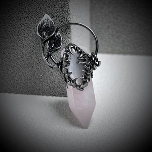 Macro detail of gothic leaf pattern silver pendant with oval grey gemstone and rose quartz