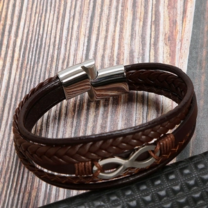 Detailed shot of brown braided leather bracelet with silver infinity symbol on wood background