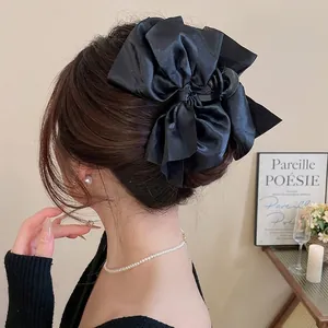 Elegant large black satin bow claw clip shown in a stylish hairstyle for women