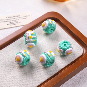 Macro detail of turquoise floral oil-painted beads on a wooden tray for DIY jewelry