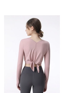 Detail of pink long sleeve yoga top with deep V-back opening and decorative waist tie
