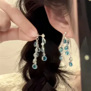 Détail de boucles d'oreilles argentées avec perles de verre bleues portées par un mannequin