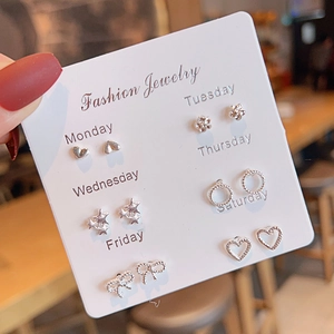 Set of six silver earrings with zircons in heart and flower shapes on a display card