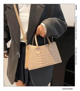 Detail of beige crocodile pattern tote bag with dual handles and stylish PU texture