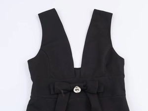 Détail d'une robe noire à col en V avec décoration de nœud et strass rond étincelant