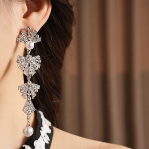 Detailed view of silver bow drop earrings with sparkling rhinestones and pearls