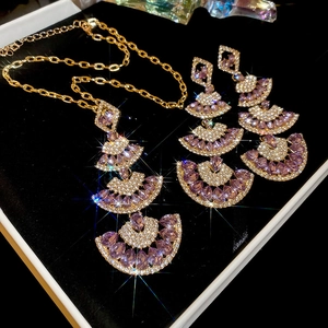 Detailed macro of gold fan pendant jewelry set with purple gemstones and zircons