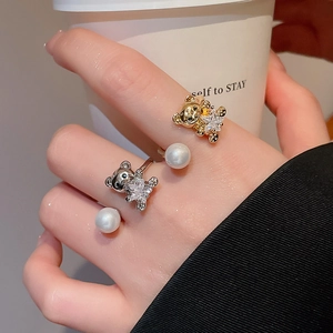 Close-up of adjustable bear and pearl rings in gold and silver plating on hand