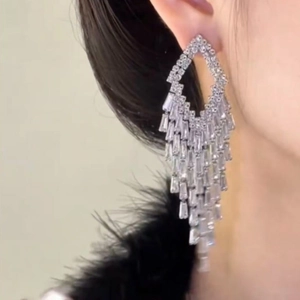 Close-up of sparkling silver tassel earrings with geometric crystals worn by a model