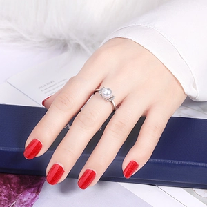 Detail of elegant silver ring with a white pearl and sparkling cubic zirconia on finger