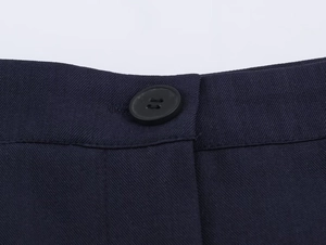 Close-up of navy blue twill fabric texture and black four-hole button on the trousers
