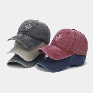 Detail view of four vintage washed cotton baseball caps with sun embroidery in various colors