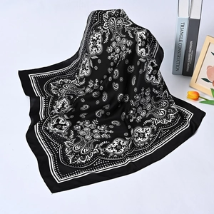 Detail of a black square silk scarf with white paisley patterns on a stylish background