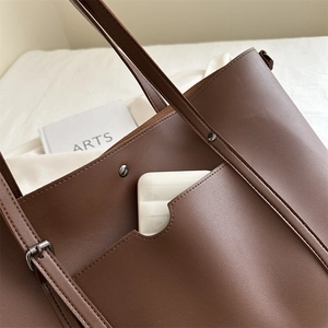 Brown leather large capacity tote bag with front pocket and decorative metal rivets