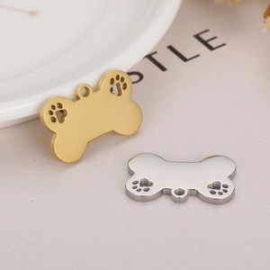 Close-up of bone-shaped metal pet ID tags with hollow paw print in gold and silver