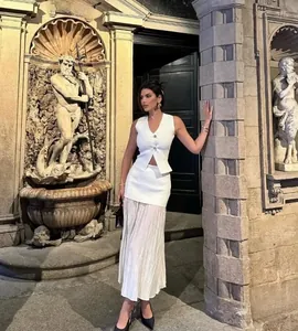 Détail d'un ensemble gilet en maille blanche et jupe longue plissée en extérieur élégant