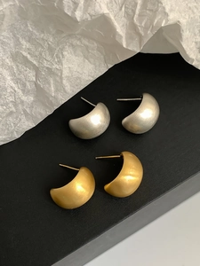 Macro detail of crescent matte geometric earrings in gold and silver finish